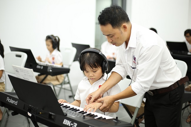 51 38 39 3. Thay Luu Quoc Toan dang huong dan hoc sinh su dung nhac cu piano trong gio Am nhac Những người ngày đêm miệt mài dũa ngọc tại IEC Quảng Ngãi